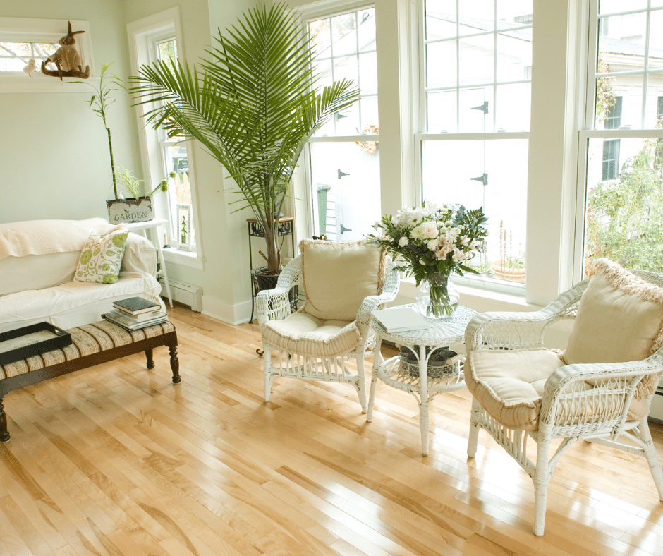 sunroom with houseplants, lots of windows, hardwood floors, and white patio furniture